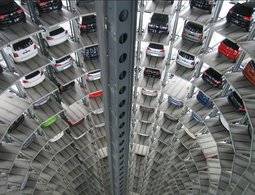 Vários carros estacionados em prédio automotivo vertical, simbolizando diversidade de veículos protegidos pelo seguro auto.