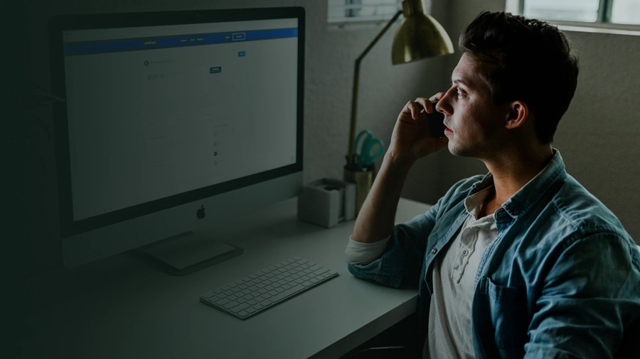 Cliente ao telefone, sentado em frente ao computador, ligando para contratar um seguro e tirar dúvidas sobre coberturas.